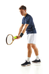 Concentrated man in his 30s, tennis player in blue shirt standing with racket, serving ball isolated over white background. Concept of professional sport, competition, game, math, hobby, action