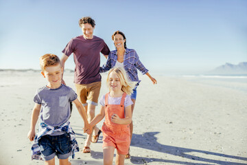 Happy family with small children walking on the beach