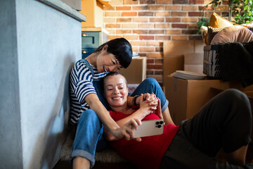 Lesbian couple capturing a selfie amidst moving boxes