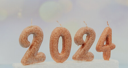 Candle numbers 2024 with festive gold star garland on pink.