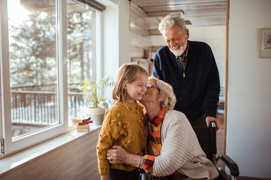 Caring little granddaughter with grandparents at home