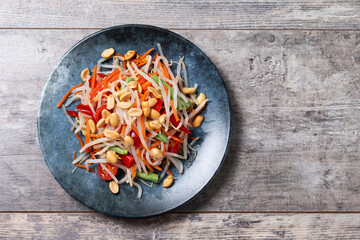 Green Papaya Salad, som tam thai on wooden table. Top view. Copy space