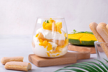 Trifle dessert with mango and ladyfinger cookies served in a glass. Tiramisu cake variation