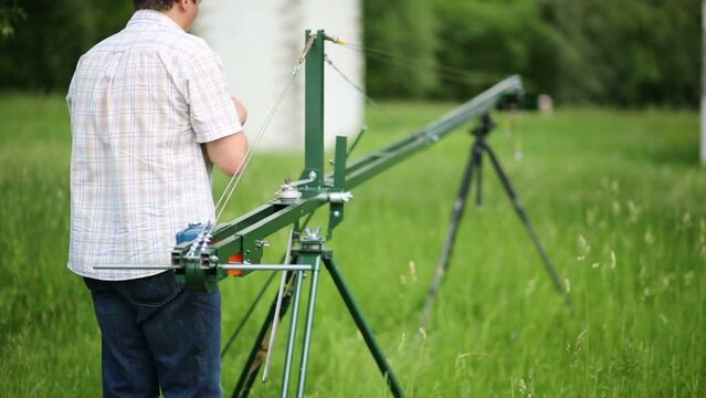 Man installs homemade crane for camera, shooting outdoors 