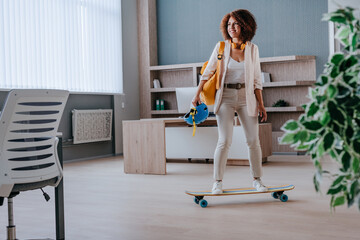 Elegant businesswoman in casual clothes riding on skateboard
