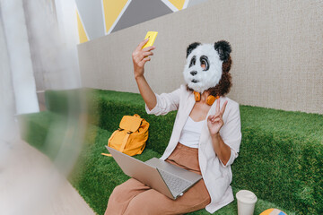 Businesswoman in mask of panda working in the lounge zone in office
