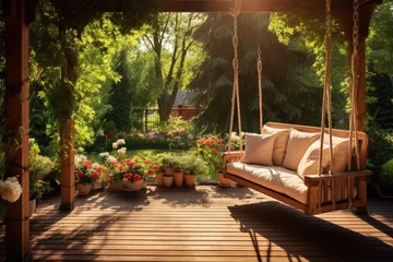 Tuinposter Beautiful wooden terrace with garden furniture and swing surrounded by greenery on a warm, summer day with warm sun light © Irina Schmidt
