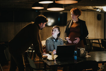 Gorgeous, pregnant businesswoman working with her colleagues, collaborating in a creative office, discussing market analysis and profitable advertising strategy.