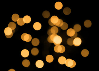 Golden bokeh lights in blur on black background. Selective focus.