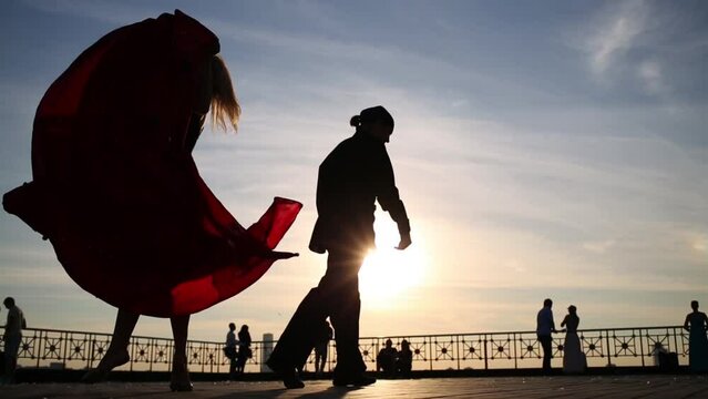 Silhouette of couple dancing outdoor against sky with sun