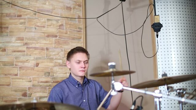 Young male drummer plays in modern recording studio 
