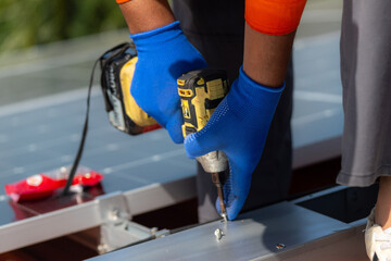 close up hand using drill driver equipment on structure. Engineer man is working to construct solar panels system on roof. Installing solar photovoltaic panel system. Renewable clean energy technology