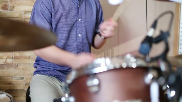 Hands of young male drummer playing in modern recording studio 