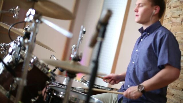 Handsome male drummer playing in modern recording studio 