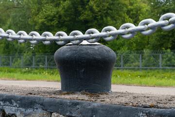 An anchor chain over a cast iron bollard on an old pier.