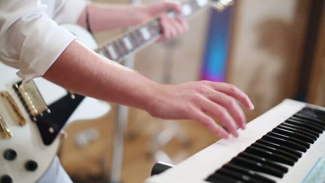Hands of man playing guitar and keyboard in recording studio