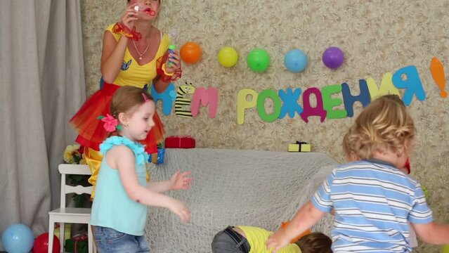 kids catch soap bubbles, which lets entertainer at party
