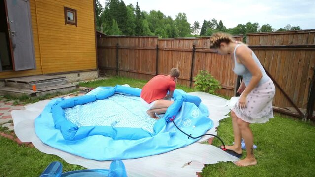 Man and woman is pumped large inflatable pool for children