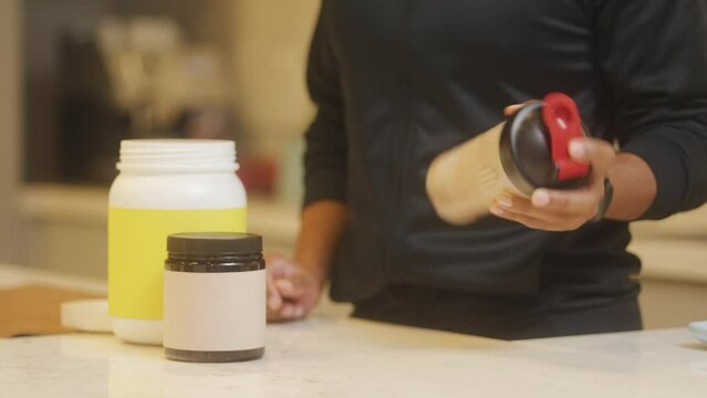 Healthy Lifestyle Choices in Modern Kitchen. Man Mixing Chocolate-Flavored Whey Protein in a Shaker Bottle. Emphasis on Supplements and Wellbeing for Optimal Fitness Regimen