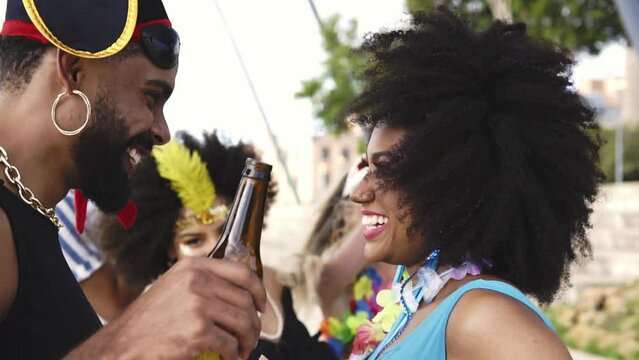 Carnaval in Brasil, black couple toasting and dancing at brazilian party in costume