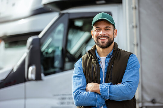 Happy confident male driver standing in front on his truck