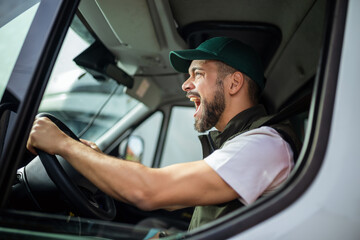 An angry truck driver is driving a truck and is annoyed with people who disturb the traffic