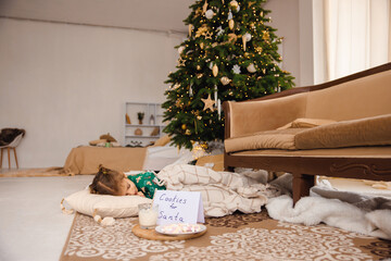 Cute girl sleeping on the floor near christmas gift boxes