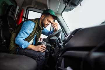 Tired truck driver holding coffee in his cabin. - Powered by Adobe