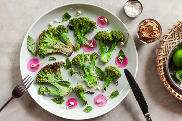 vegetarian organic broccoli cabbage bowl with marinated radish and sprouts of mash fresh meal green food cooking on a minimal concrete grey background 