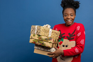 Young woman in red sweater with christmas deer holding gift boxes