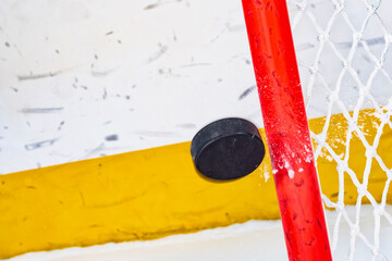 An ice hockey puck in mid-air hitting the goal post