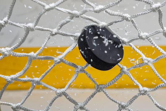 An ice hockey puck hitting the back of the net as it scores a goal