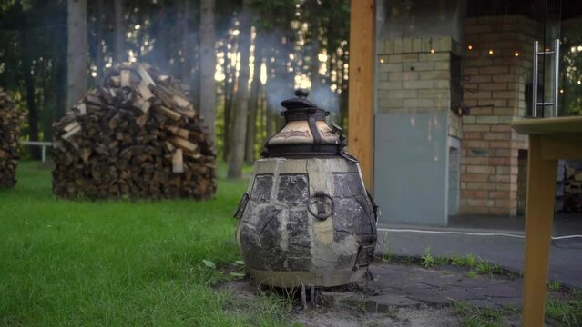 Close up smoke from modern ceramic wood-fired tandoor in outdoor kitchen. 