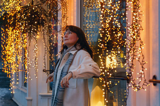 A smiling woman enjoying the charm of a Nordic small town with a new year decorations.