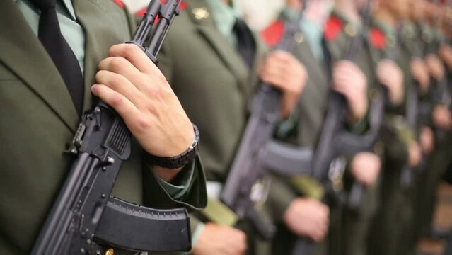 Row of hands of soldiers in uniforms with machine guns on parade
