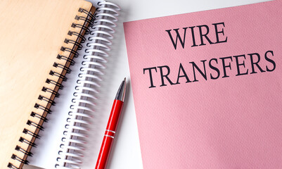 WIRE TRANSFERS word on the pink paper with office tools on white background