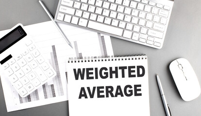 WEIGHTED AVERAGE text on a notebook with keyboard on grey background