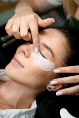 Stylist carefully corrects the patch under the eye of a beautiful woman