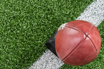 An overhead view American football on kicking tee with yard line