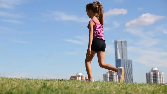 Happy little girl does cartwheels on green grass in sunny day