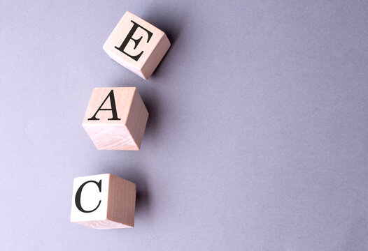 Word EAC on wooden block on the grey background