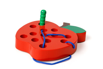 Children's wooden toy in the shape of a red apple with a worm on a rope, toy for developing fine motor skills, isolated on white background.