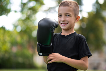 Cute boy in boxing gloves looking contented and excited
