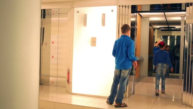 Boy and girl enter to elevator in office building