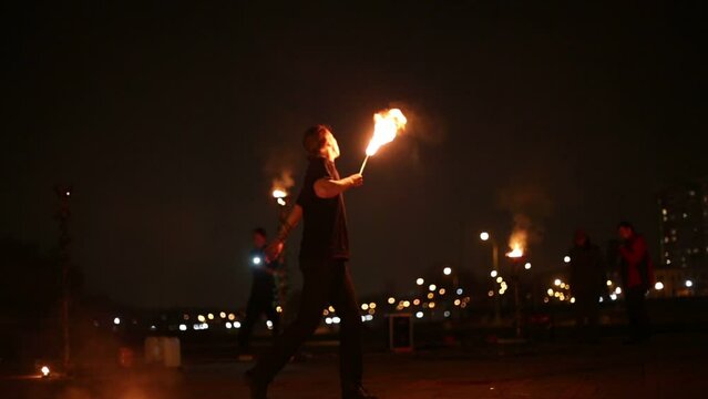 Young man makes fireballs, standing at one place and turning