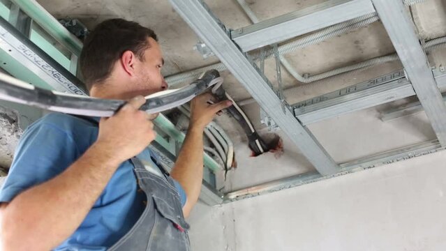 Worker sets tubes with wires on ceiling for air conditioner