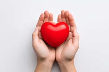Hands holding a red heart against a white background.