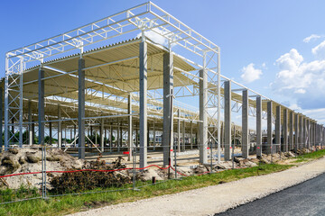 Unfinished warehouse steel frame structure on reinforced concrete supports, corrugated steel roof
