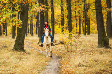 A pretty young woman and a white horse galloping through the woods