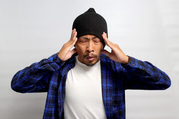 Nervous young Asian man is taking steps to calm down, focusing on breathing techniques, possibly...